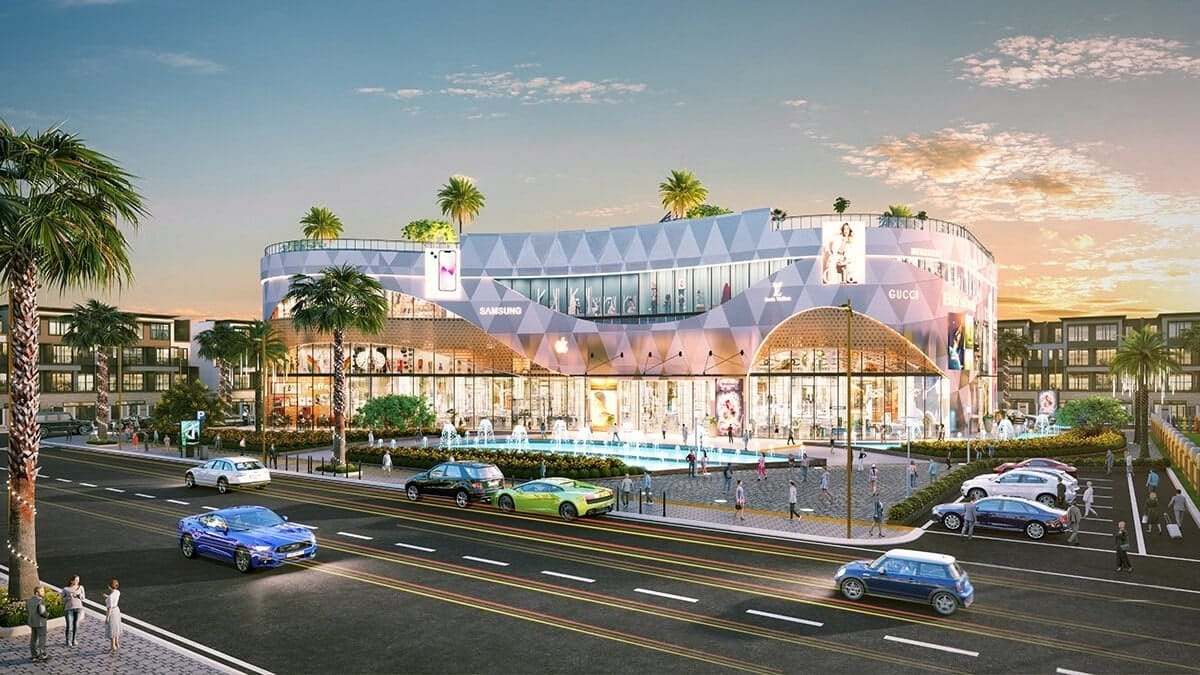 Hình ảnh phối cảnh một trung tâm thương mại hiện đại tại Alluvia City, với thiết kế kiến trúc nổi bật, mặt tiền kính lớn, đài phun nước phía trước và khu vực giao thông – cảnh quan được quy hoạch đồng bộ.